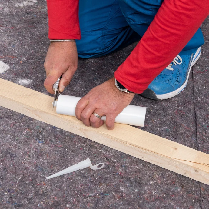 Heimwerker schneidet die &Ouml;ffnung des Injektionstrichters frei. Daneben liegt die Einf&uuml;llspitze, die im Anschluss auf den Injektionstrichter geschraubt wird.