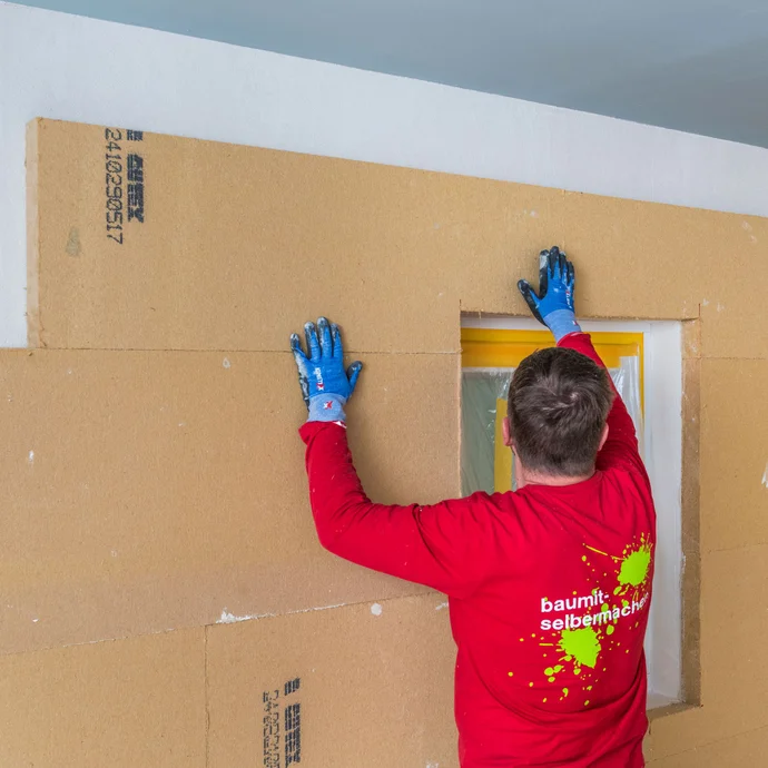 Heimwerker klebt die Holzfaserd&auml;mmplatten als Innend&auml;mmung rund um das Fenster und vervollst&auml;ndigt die D&auml;mmung. Baumit Selbermachen Anleitung.