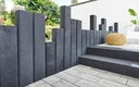 Modern terras grijs, lichte stenen platen en palissaden in antraciet.
