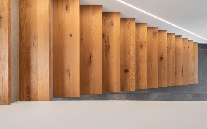 Moderne trapopgang in een eengezinswoning, van bovenaf gezien, met beton, hout, indirecte verlichting en de stralend witte, fijne afwerkpleister InStyle Edelwit.