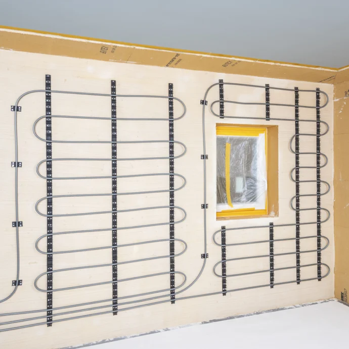Wand mit verlegter Wandheizung vor Fenster, bereit f&uuml;r Putzauftrag in Heimwerkerprojekt.