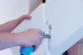 Person schneidet Dämmstoffplatte präzise mit werkzeugunterstützter Technik.