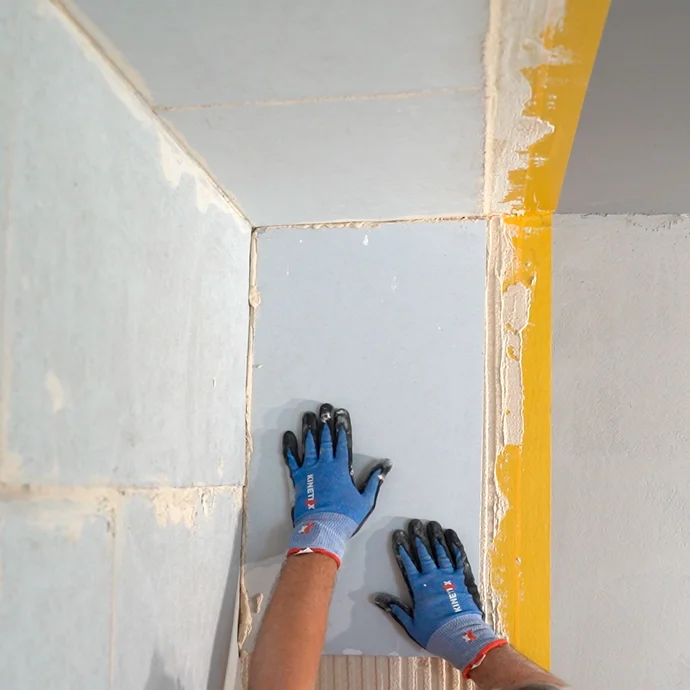 Person klebt den Anschlusskeil an die Wand.