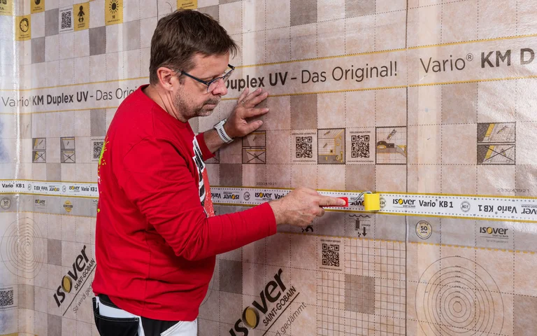 Baumit Handwerker drückt das Folienklebbeband ISOVER Vario KB1 mit einer Andruckwalz vollflächig und ohne Falten oder Blasen fest an. Baumit Anleitung zum Selbermachen - Dampfbremse bei einer Innendämmung mit Tragkonstruktion einbauen.