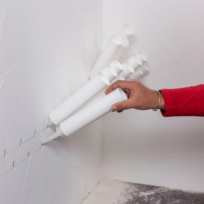 Handwerker setzt die vorbereiteten Injektionstrichter in die zuvor gebohrten L&ouml;cher ein.