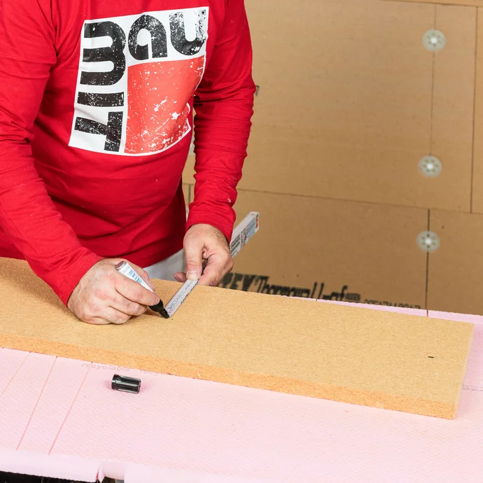 Auf der zugeschnittenen Holzfaserdämmplatte für die Laibung am Fenster wird der Bereich eingezeichnet, wo der Klebemörtel aufgetragen wird. Baumit Anleitung zum selbermachen.