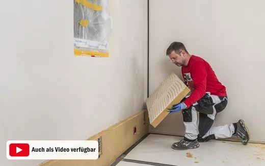 Heimwerker klebt die Holzfaserdämmplatte an die Wand. Innendämmung selber an die Wand kleben. Baumit DIY-Anleitung.