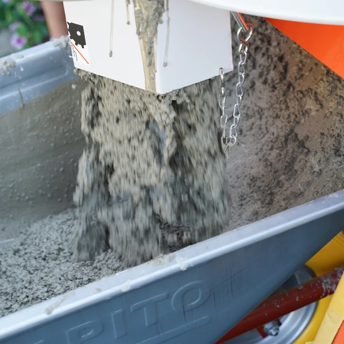 Durch das Öffnen der vorderen Klappe des Chargenmischers PFT MULTIMIX 140 plus fließt der frisch angemischte Beton direkt in eine Schubkarre. Schubkarre fasst zwei Säcke Trockenbeton (ca. 26 Liter Frischmörtel).