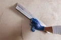 Baumit kalkpleister RK 39 buiten wordt geëgaliseerd met een vlakspaan.