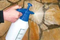 Fugen von Natursteinplatten mit Sprühflasche benetzen, um Mörtelreste zu entfernen.