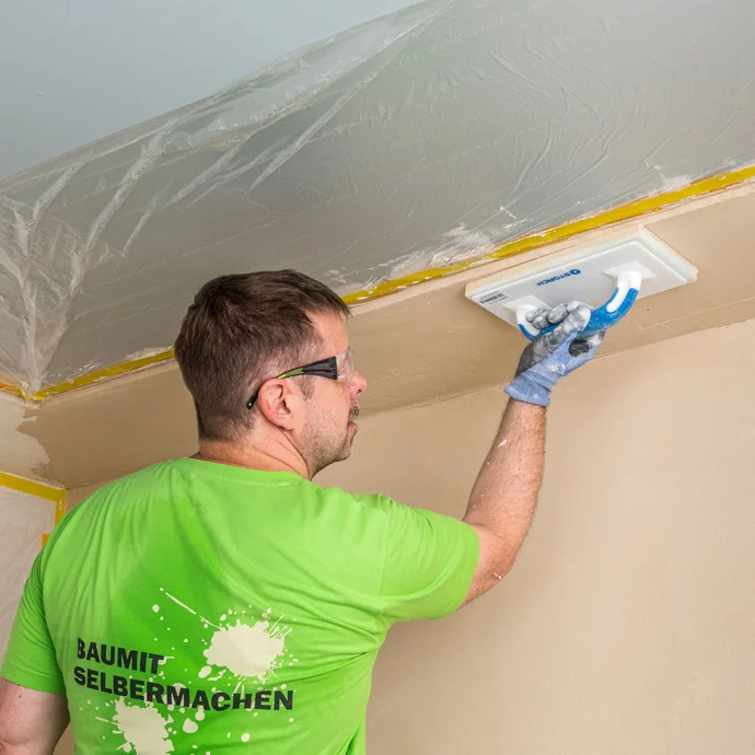 Heimwerker filzt den D&auml;mmkeil im Deckenbereich mit dem Filzbrett ab &ndash; Baumit Kalkin Kalkspachtel multifine an schwer zug&auml;nglichen Stellen gleichm&auml;&szlig;ig und sauber filzen, Baumit Selbermachen Anleitung.