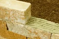 Trockenmauer aus Naturstein mit frischem Mörtel in Fugen, perfekt für DIY-Gartenprojekte.