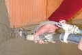 Ein Handwerker trägt Putz mit einer Spritzpistole auf eine Ziegelwand auf.