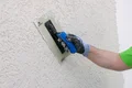 Close-up: De structuur van de roughcast wordt behandeld met een wrijfplank.